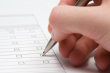 фотографія руки з ручкою, яка вибирає на бланку певні квадратики 